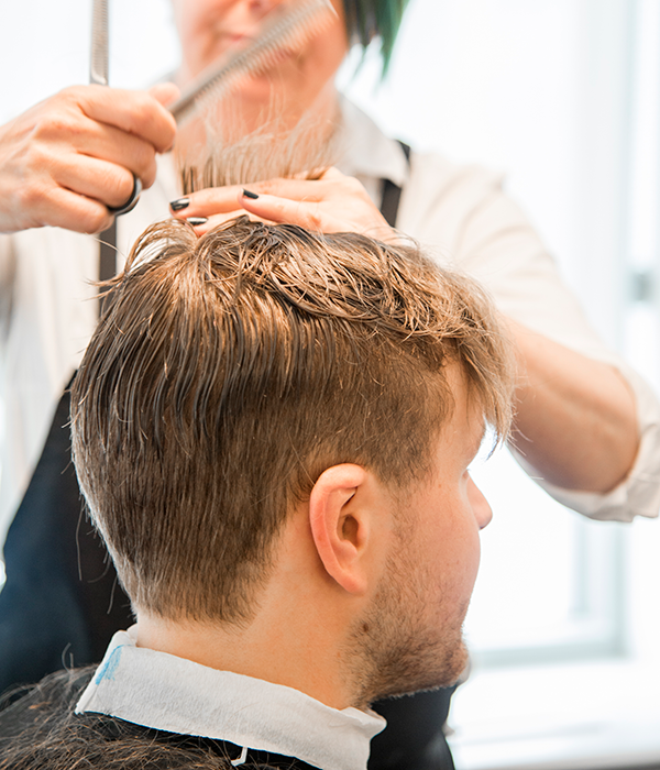 En mann med blondt hår stusser håret hos frisøren