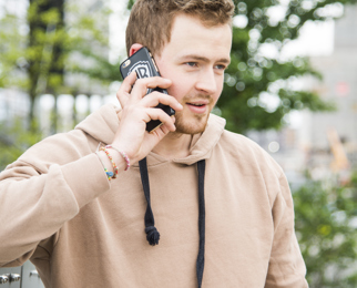 En ung mann med hårdel fra Apollo Hårsenter snakker i mobiltelefonen
