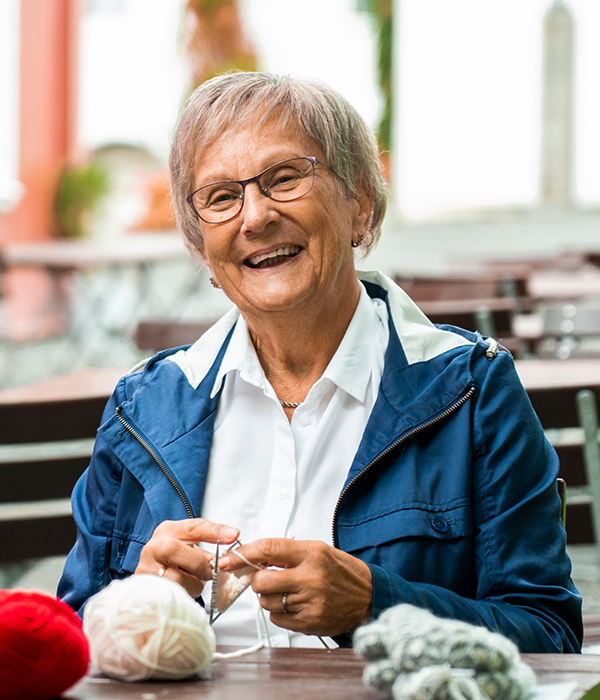 En eldre kvinne med grått hår smiler mot kamera