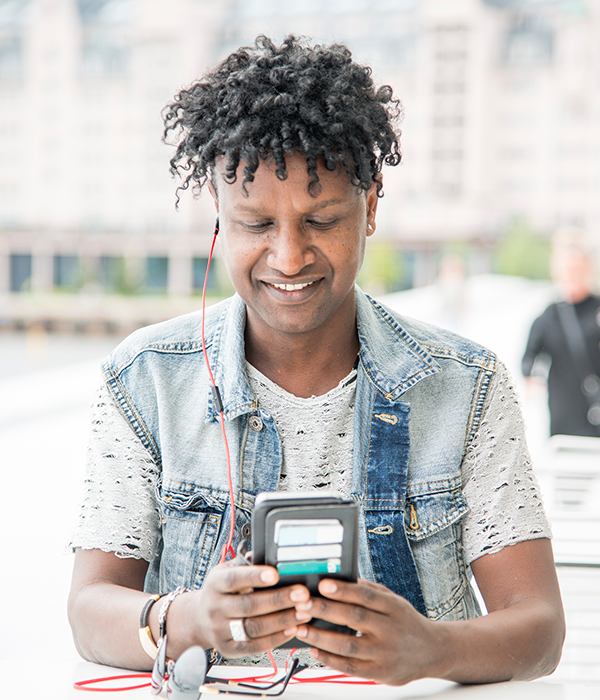 En mann med svarte krøller og denimjakke ser på mobiltelefonen sin