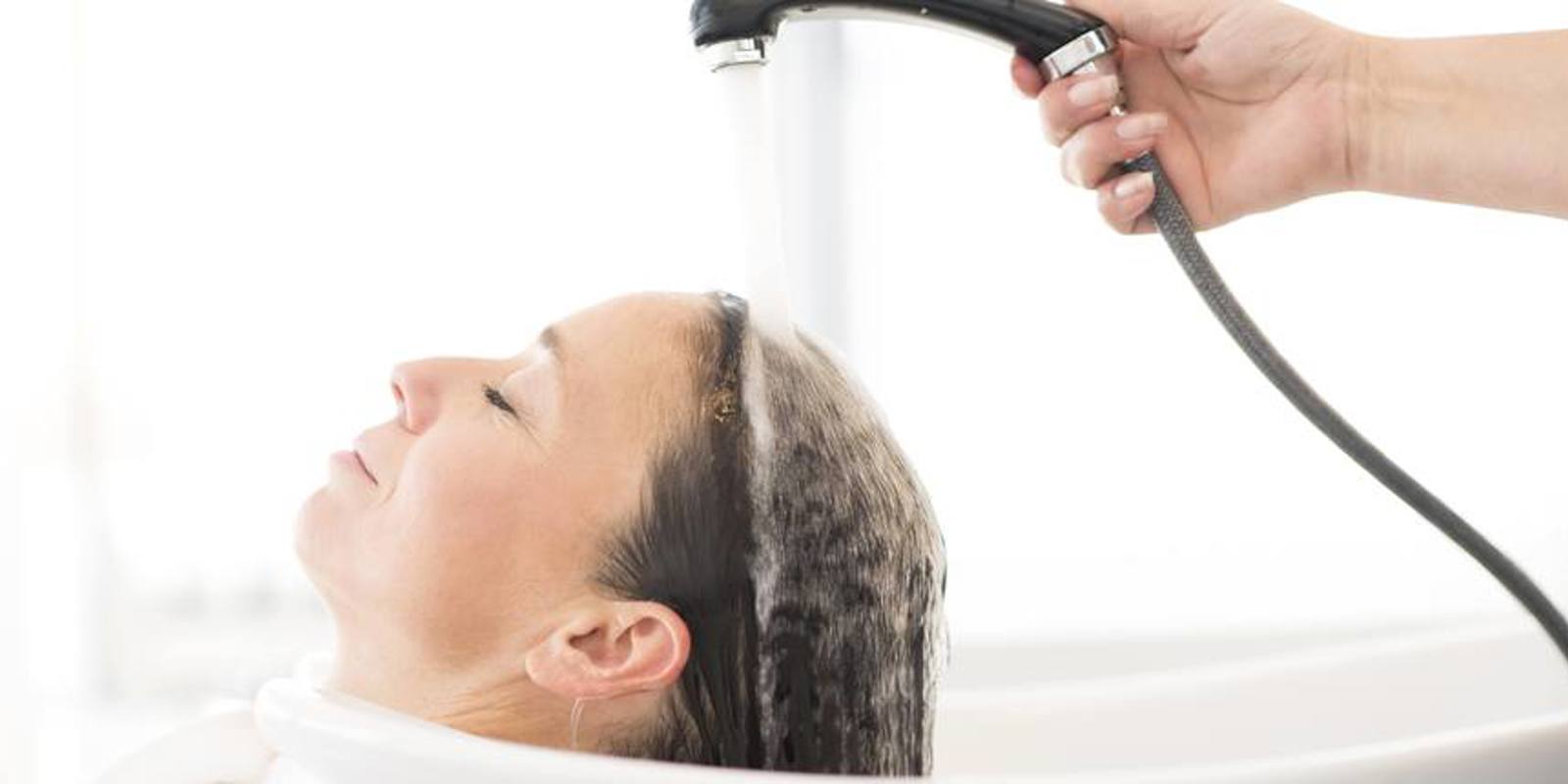 En kvinne med mørkt hår får håret vasket hos frisøren