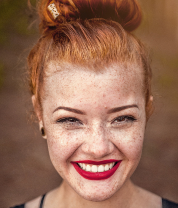 En kvinne med rødt hår, fregner og rød leppestift